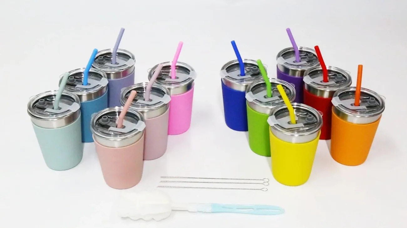 Set of 12 colorful 12oz spill-proof stainless steel kids cups with matching straws and cleaning brushes on a white background.